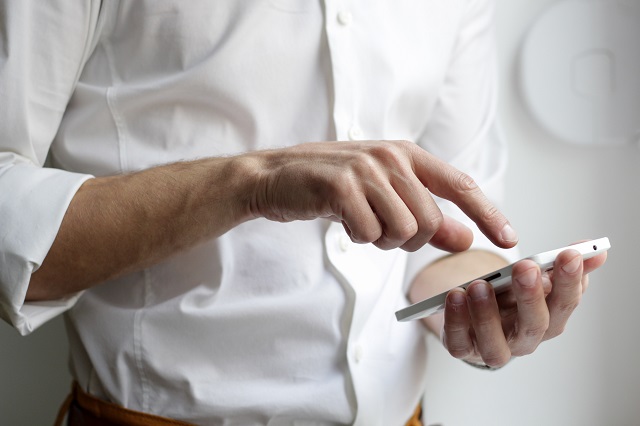 Vivo Empresas: Foto de um homem segurando um celular com uma mão enquanto toca nele com a outra.